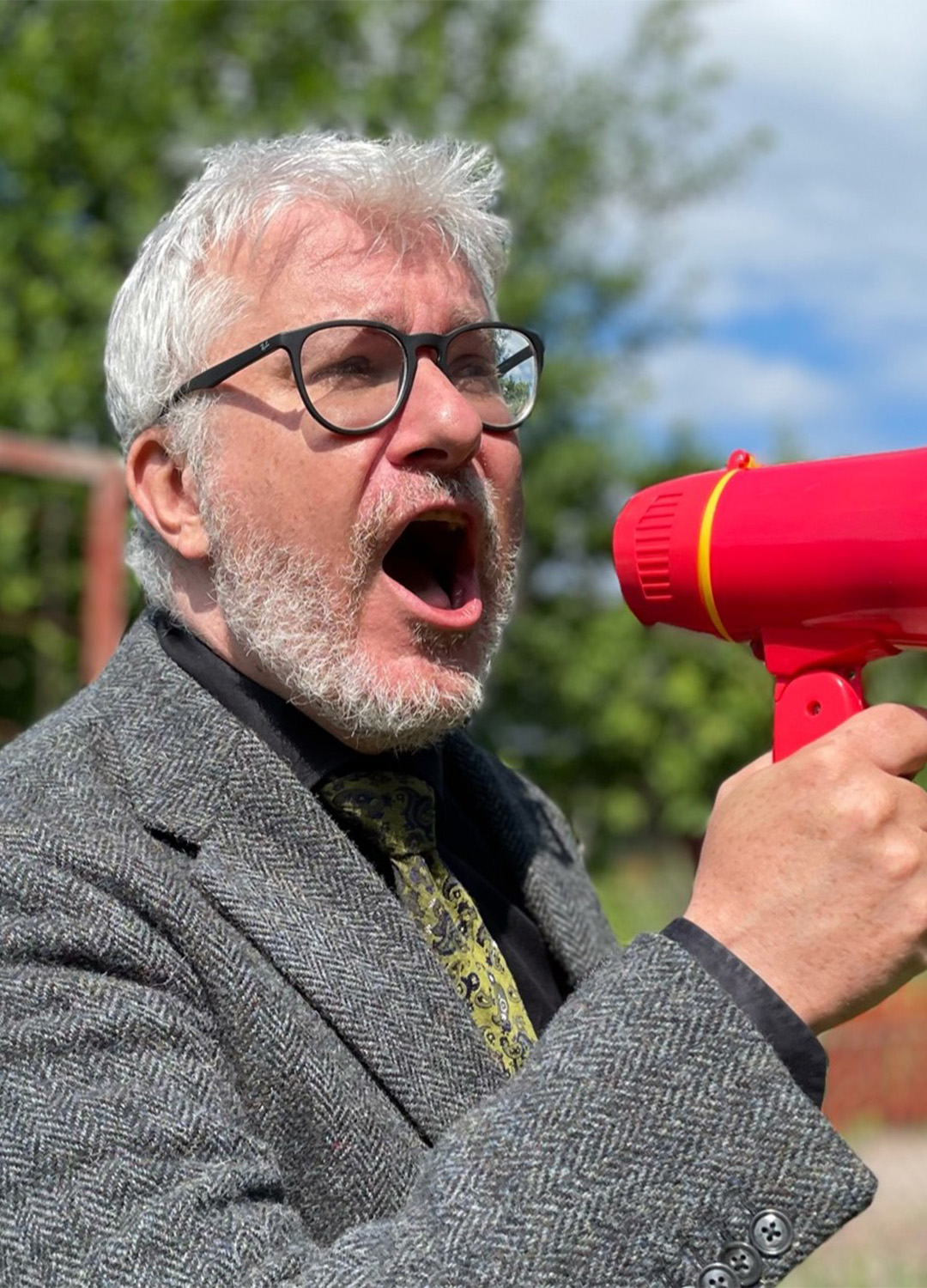 En man skriker in i en röd leksaksmegafon. 