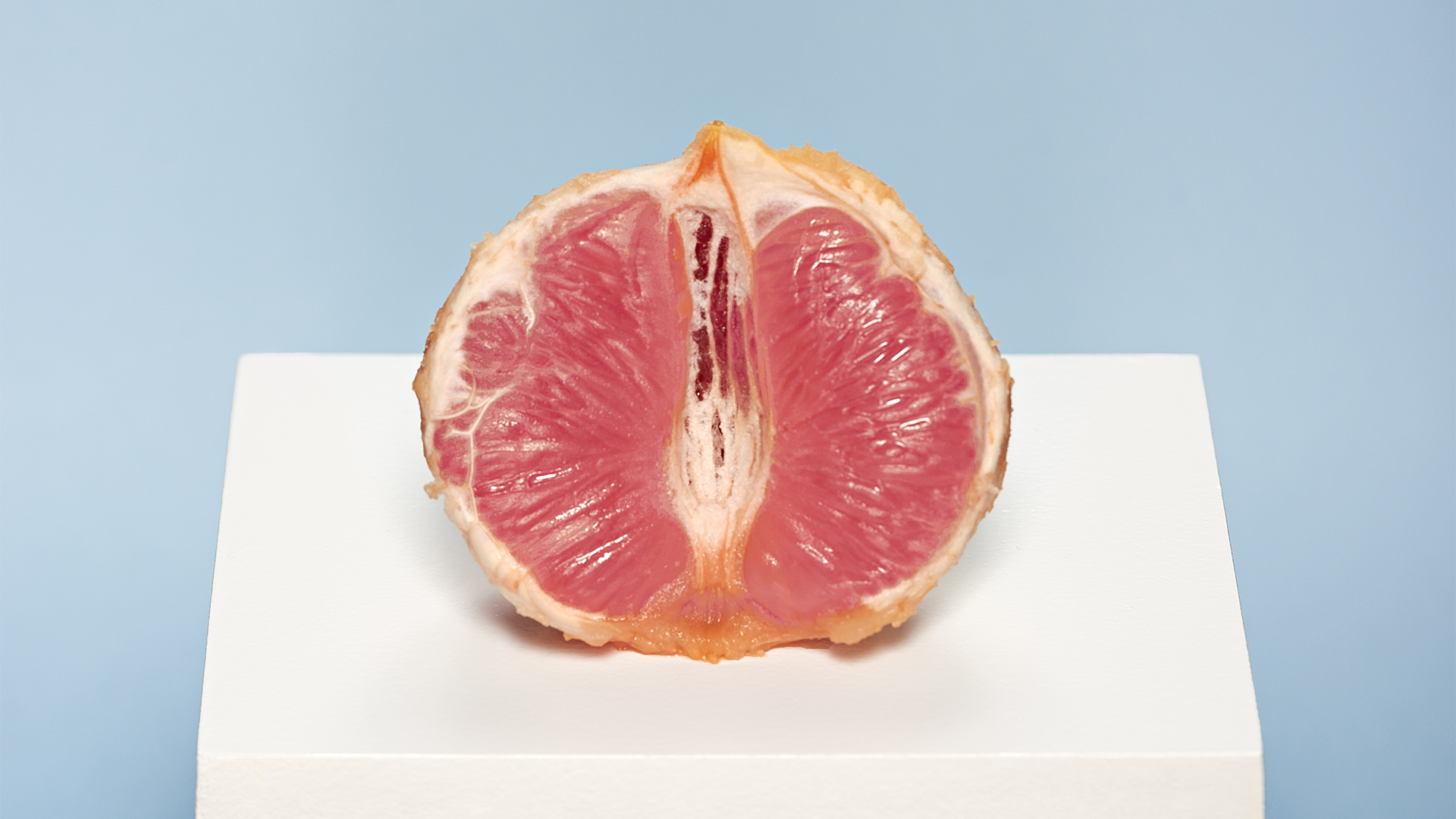 Klickbar bild Kunskapens frukt. En halverad grapefruit på ett podie. 